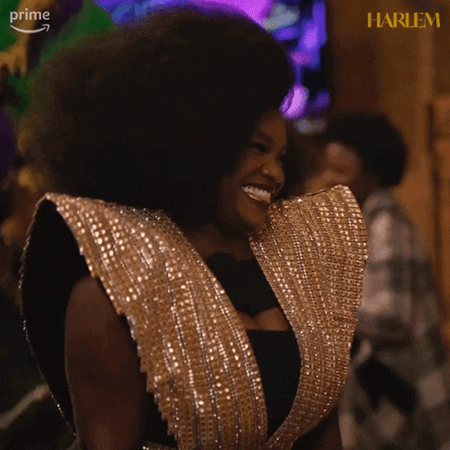 a woman with a big afro is smiling in front of a sign that says harlem on it