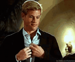 a man in a suit and tie is adjusting his tie