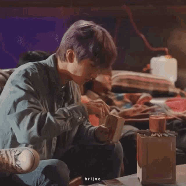 a man with purple hair is lighting a candle with a match