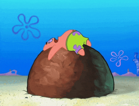 patrick star is laying on top of a large rock in the sand