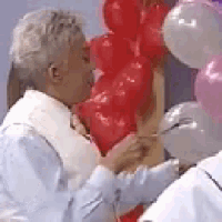 a man is kissing a woman while holding balloons .