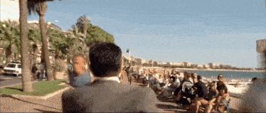 a man in a suit stands in front of a crowd of people on the beach