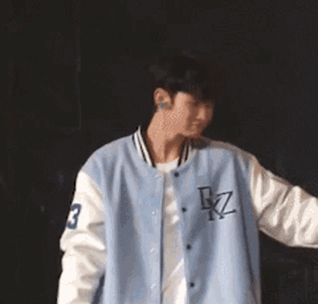 a man wearing a blue and white baseball jacket with the letter bz on it