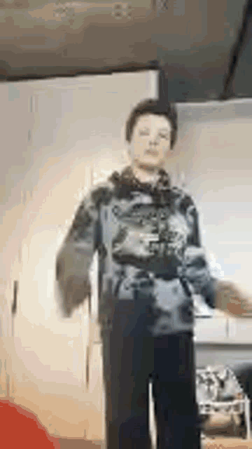 a young man is dancing in a kitchen in a blurry photo .
