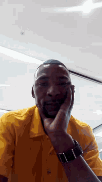 a man wearing a yellow shirt has his hand on his chin