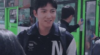 a young man is standing next to a bus and smiling .
