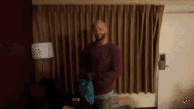 a man with a beard is standing in front of a curtain in a room