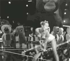 a black and white photo of a woman on a stage with stuffed animals