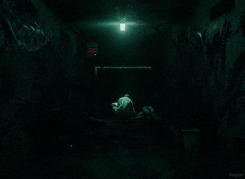 a man in a lab coat is walking down a dark hallway with a sign that says exit