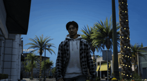 a man wearing a plaid shirt is walking down a street with palm trees in the background
