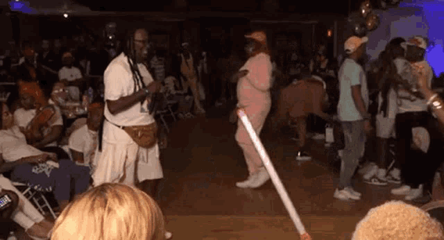 a group of people are dancing on a dance floor with a mop in the foreground .