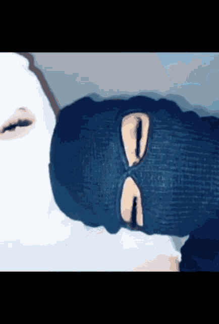 a person wearing a blue ski mask and a white ski mask is laying on a bed .