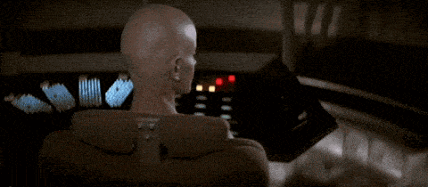 a bald woman is sitting in a chair in front of a control panel