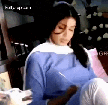 a woman in a blue and white dress is sitting on a couch holding a white dog .