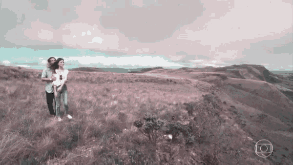 a man and a woman standing on top of a hill with the letter o on the bottom