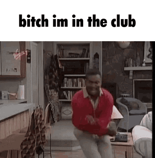 a man is dancing in a living room with the words `` bitch im in the club '' written above him .