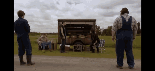 a man in overalls is standing in front of a truck with the trunk open