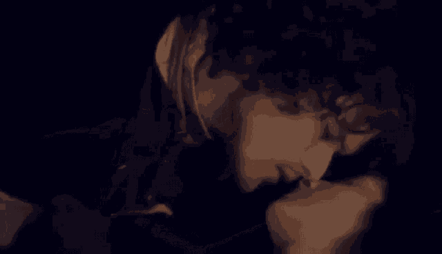 a man and woman are kissing in the dark .