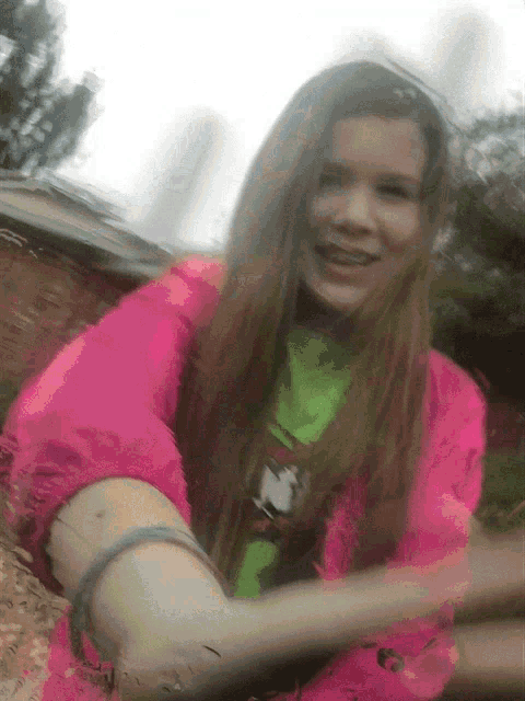 a young girl wearing a pink jacket and a green shirt