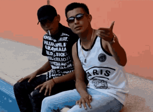 two young men sitting next to each other one wearing a shirt that says aris