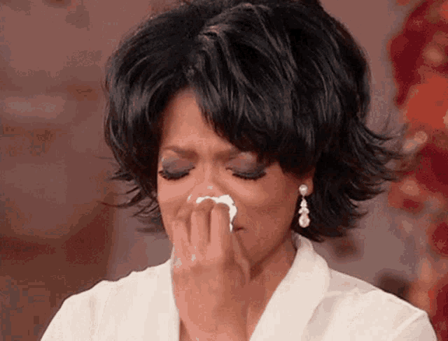 a woman is crying while holding a napkin to her nose