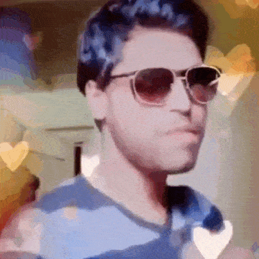 a close up of a man wearing sunglasses and a blue shirt .