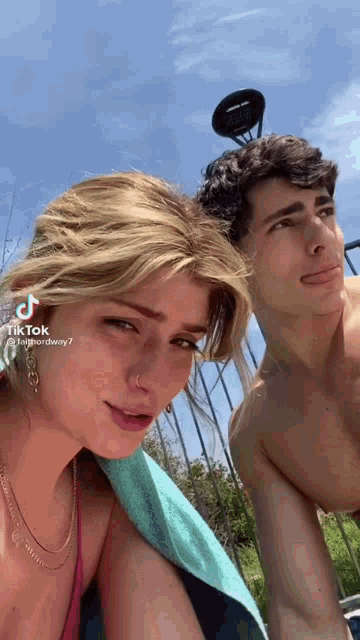 a man and a woman are posing for a picture and the woman is wearing a pink bikini top .