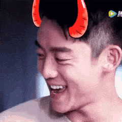 a man wearing devil horns on his head is smiling