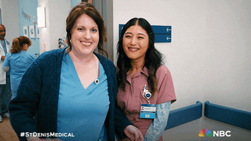 two nurses are posing for a picture in a hospital hallway with the nbc logo in the background