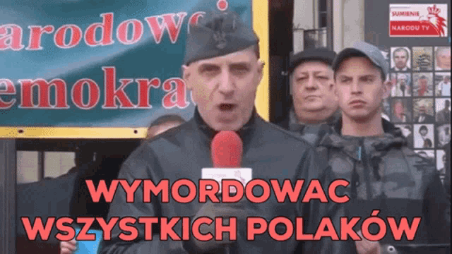a man speaking into a microphone with the words wymordowac written in red