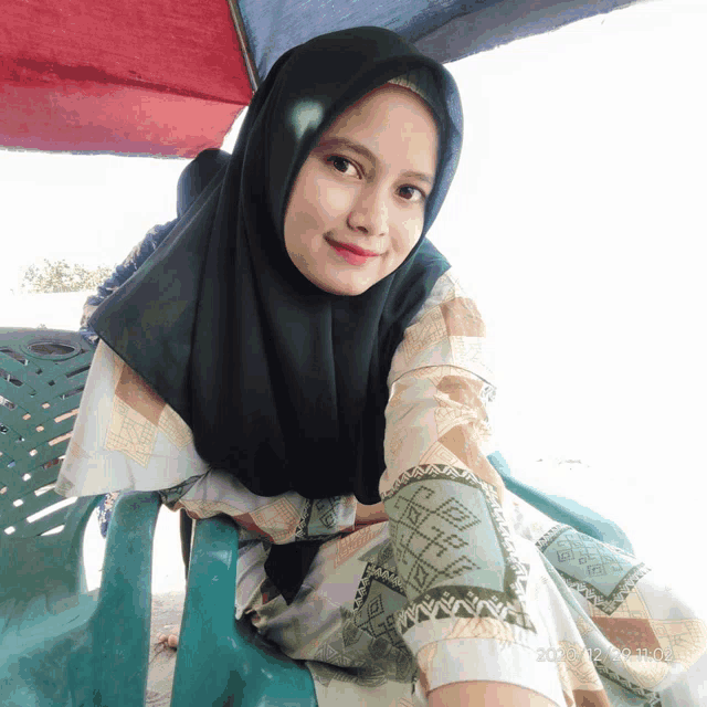 a woman wearing a hijab is sitting in a chair with a photo taken on february 28th 2020