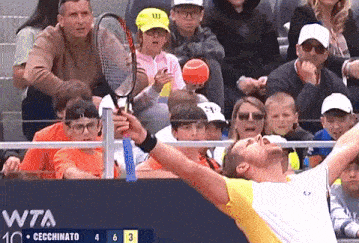 a man is holding a tennis racquet in front of a crowd at a wta tournament