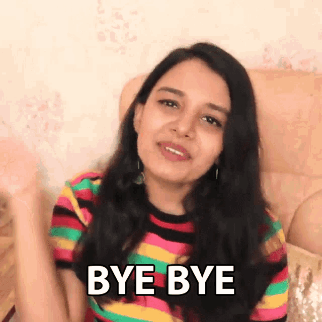 a woman in a colorful striped shirt is saying bye bye