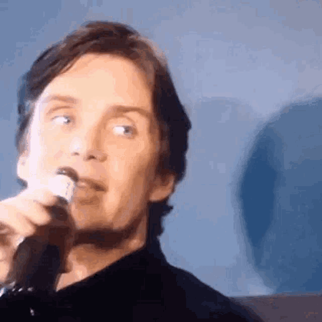 a man is holding a microphone in front of his mouth .