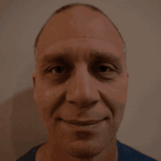 a close up of a man 's face with a blue shirt