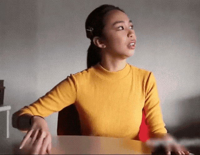 a woman in a yellow top is sitting at a table