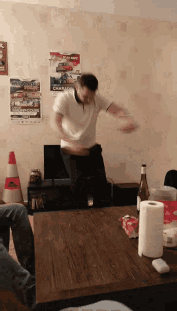 a man dancing in a living room with a poster on the wall that says champions