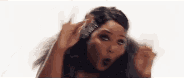 a woman is brushing her hair with a comb and a clip .