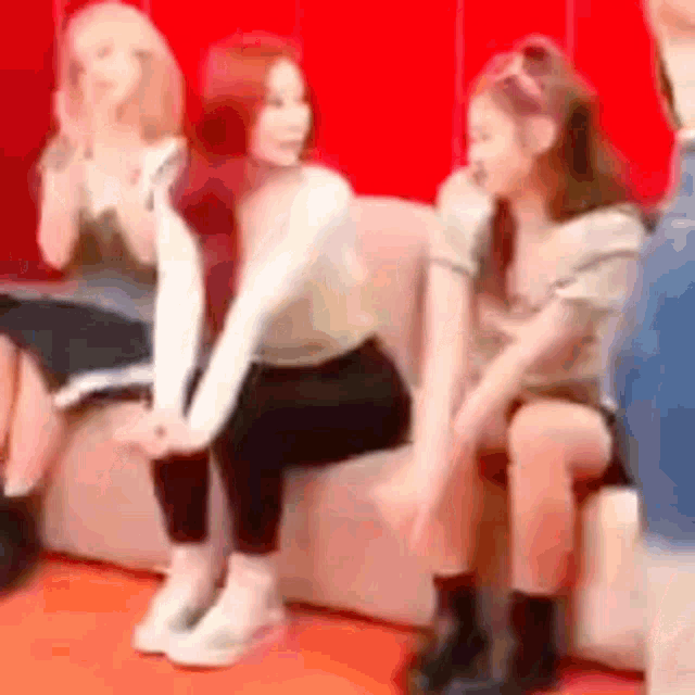 three women are sitting on a couch in a room .