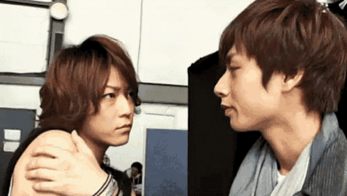 two young men are hugging each other and looking at each other in a room .