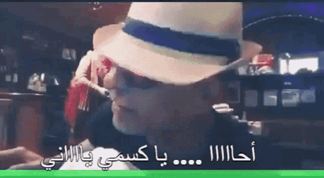 a man wearing a hat and sunglasses with arabic writing on the bottom