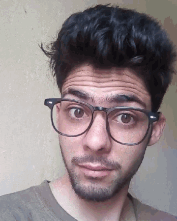 a young man with glasses and a beard makes a funny face