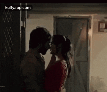 a man and a woman are kissing each other in front of a door .