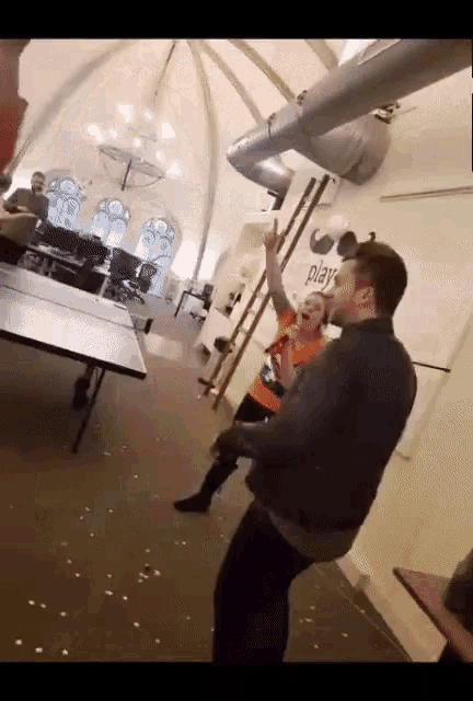 a group of people are playing ping pong in a room with a sign that says play on it