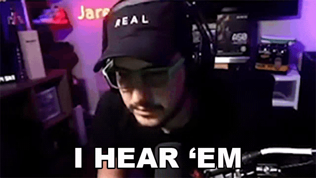 a man wearing headphones and a hat says i hear ' em