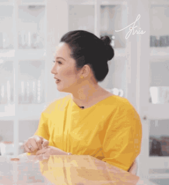 a woman in a yellow shirt is sitting at a table with the name friis on the bottom right