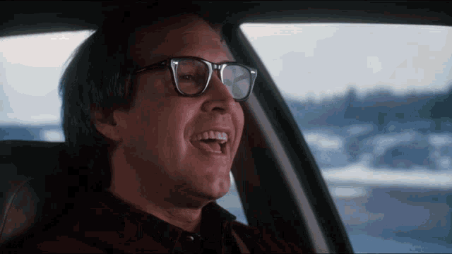 a man wearing glasses is sitting in a car and smiling