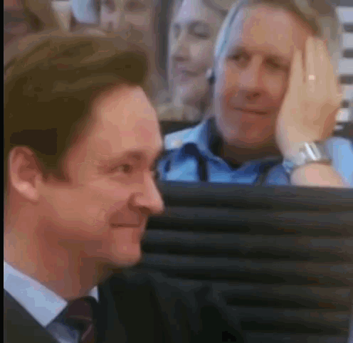a man in a suit and tie is sitting in a chair and smiling .