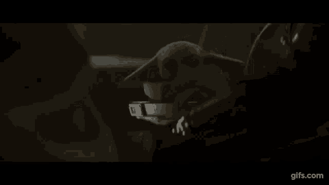 a person is sitting in a chair in a dark room with a glowing object in the background .