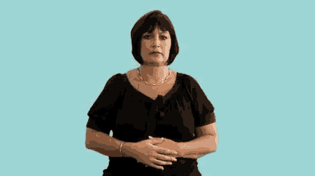 a woman in a black shirt and necklace is holding her stomach .